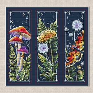 May include: A set of three vertical cross-stitch patterns on a dark blue background. The first panel features mushrooms and ferns, the second shows yellow dandelion flowers and leaves, and the third displays a butterfly with a dandelion seed head.