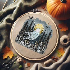 May include: A cross-stitch embroidery hoop featuring a spooky ghost design. The artwork depicts a ghost in a forest with a full moon, bats, and stars. The color palette includes blues, greens, and yellows, with a neutral background. The hoop is surrounded by autumn-themed decorations.
