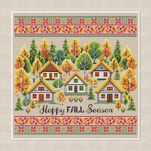 May include: Cross-stitch design featuring a village scene with houses, trees, and the text "Happy FALL Season." The houses have thatched roofs and are surrounded by autumn trees in shades of green, yellow, and orange. The design includes decorative borders.
