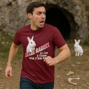 Puede incluir: Camiseta granate con un gráfico de conejo blanco y el texto "KILLER RABBIT". La camiseta también tiene el texto "It's Got A Vicious Streak A Mile W". Una persona lleva la camiseta y corre.