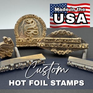 May include: A collection of custom hot foil stamps in various shapes and sizes. The stamps are made of metal and feature intricate designs and text. The image includes the text "Made in the USA" and "Custom Hot Foil Stamps".