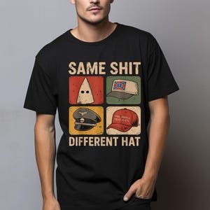 May include: Black t-shirt featuring the text "SAME SHIT DIFFERENT HAT" above four images of hats. The hats include a white hood, a Confederate flag hat, a military hat, and a red "Make America Great Again" hat.