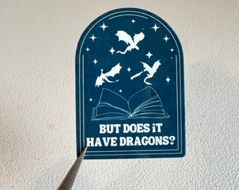 May include: A blue sticker with a white open book and three white dragons flying above it. The text on the sticker reads "But does it have dragons?"