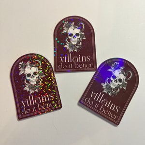 May include: Three holographic stickers with a burgundy background and a skull with a snake wrapped around it. The text on the stickers reads "villains do it better".