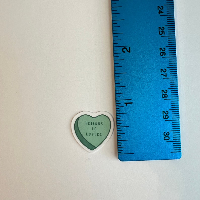 Puede incluir: Una pegatina verde en forma de coraz&oacute;n con el texto "Friends to Lovers" en ella.