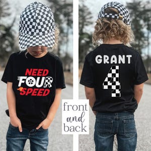 以下が含まれることがあります： 黒のTシャツに「Need Four Speed」の文字と、前面に市松模様の旗のデザインが施されています。Tシャツの背面には「GRANT」という名前と、市松模様の旗のデザインが施された「4」という数字が書かれています。Tシャツは、白黒の市松模様の帽子をかぶった子供が着用しています。