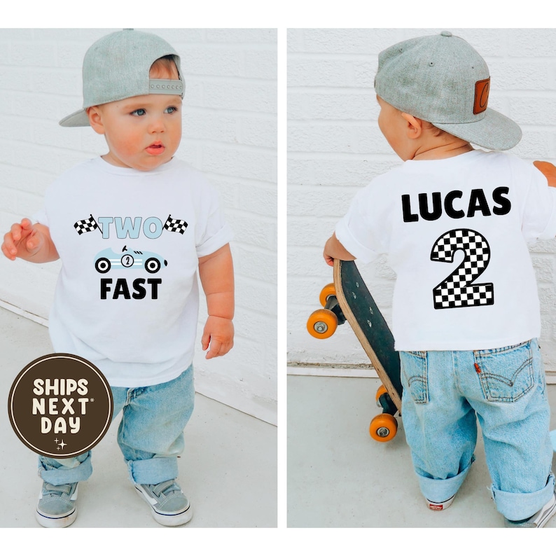 May include: A white toddler t-shirt with a race car design and the words "TWO FAST". The back of the shirt has the name "LUCAS" and a checkered number "2". The child is wearing blue jeans and a gray baseball cap.