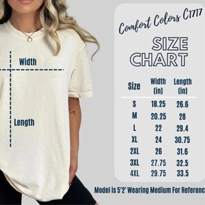 May include: Size chart for a t-shirt with measurements in inches. The chart shows the width and length of the shirt in sizes S, M, L, XL, 2XL, 3XL, and 4XL. The model is 5'2' and wearing a size Medium.