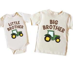 May include: Two cream colored shirts with brown text and a green tractor graphic. One shirt says "Little Brother" and the other says "Big Brother".
