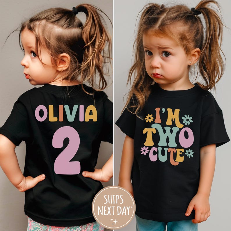 Może przedstawiać: Czarny t-shirt z kolorowym nadrukiem "I'm Two Cute" z przodu i spersonalizowanym imieniem i numerem z tyłu. Koszulkę nosi dziecko.