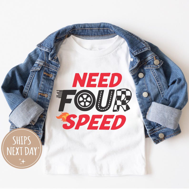 以下が含まれることがあります： 白いTシャツに赤い文字で「Need Four Speed」と書いてあります。文字はタイヤ、チェッカーフラッグ、炎でスタイリッシュにデザインされています。