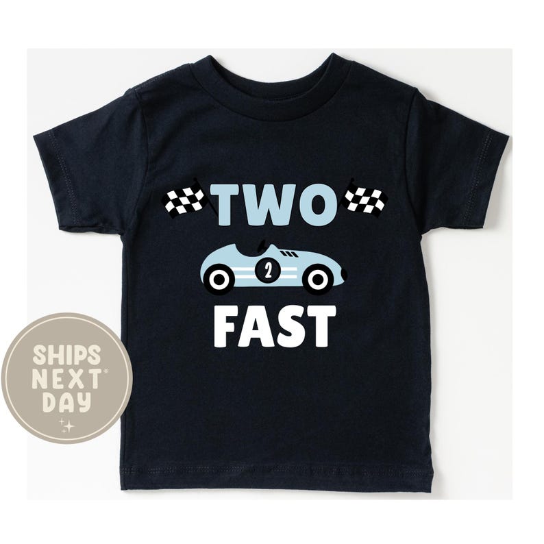 May include: Navy blue toddler t-shirt with a light blue race car graphic and the words "TWO FAST" in white. The race car has the number 2 on the side and two checkered flags. A fun shirt for a child's second birthday.