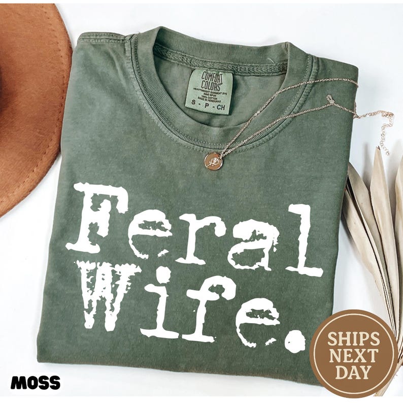 May include: A green t-shirt with the text "Feral Wife." printed in white. The shirt is made of a soft, comfortable material.