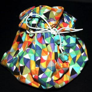 May include: A colorful drawstring pouch with a geometric pattern in shades of red, yellow, green, blue, and purple. The pouch is tied with a white cord and has turquoise beads.