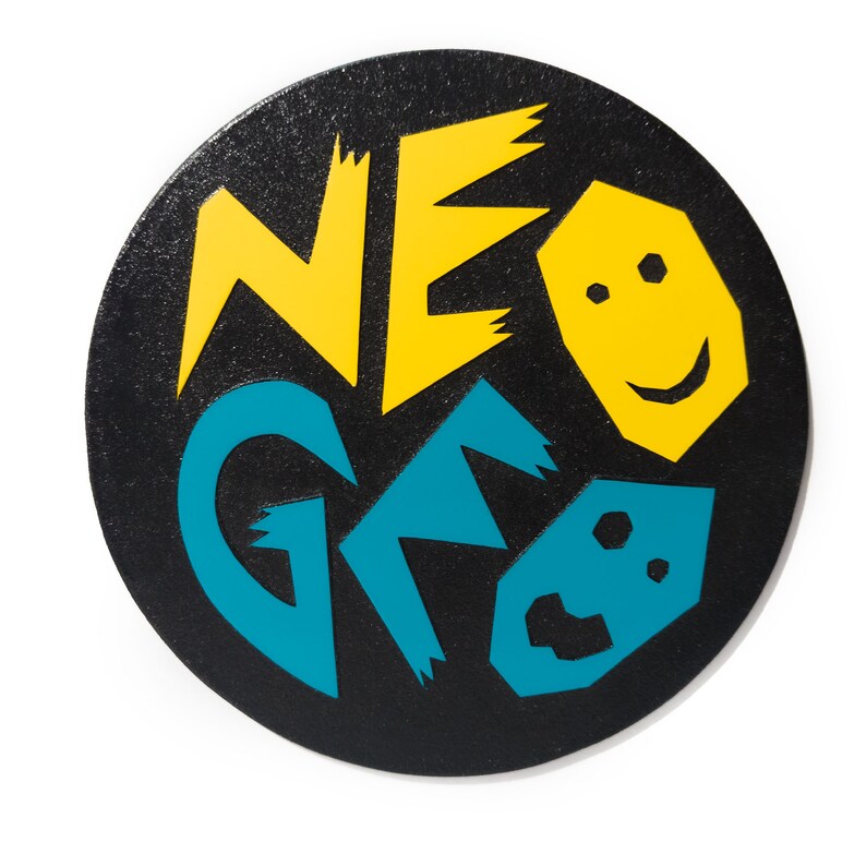 Może przedstawiać: Czarne koło z ż&oacute;łto-niebieskim wzorem graficznym z napisem "NEO GEO".