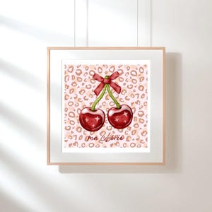 May include: A pink and brown leopard print background with two red cherries with green stems and a red bow. The text "ma Cherie" is written in cursive below the cherries.