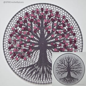 May include: A circular, crocheted wall hanging featuring a tree design. The tree trunk and branches are dark gray, with pink and purple flower accents. The background is a dark gray, open-weave pattern. The text "@2PiRCrochetbyLara" is visible.