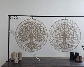 May include: Two circular wall hangings with tree designs. The trees are intricately crocheted in a neutral beige color, with detailed branches and roots. The hangings are suspended from a black metal rod, creating a natural, earthy aesthetic.