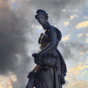 May include: A weathered stone statue of a woman holding a basket of fruit, set against a dramatic sky with clouds and a sunset. The sculpture is detailed, with flowing drapery and a classical style.