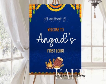 May include: A blue welcome sign with orange floral garlands, a bonfire, a drum, and the text "Welcome to Angad's First Lohri".