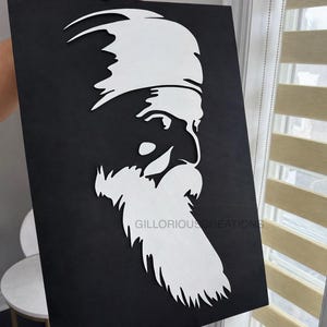 Può includere: Un'opera d'arte da parete rettangolare nera con una silhouette bianca tagliata al laser di una figura barbuta che indossa un turbante di profilo. Il design è centrato sullo sfondo nero e il testo GILLORIOUSCREATIONS è stampato in piccole lettere.