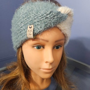 Pode incluir: Uma faixa de cabeça de malha azul e branca com uma etiqueta de couro marrom que diz "KK CO."