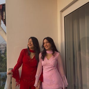 May include: A red long-sleeved tunic with flared sleeves and matching wide-leg trousers, alongside a light pink long-sleeved tunic with flared sleeves and matching wide-leg trousers, both featuring V-necklines and delicate tonal embroidery.