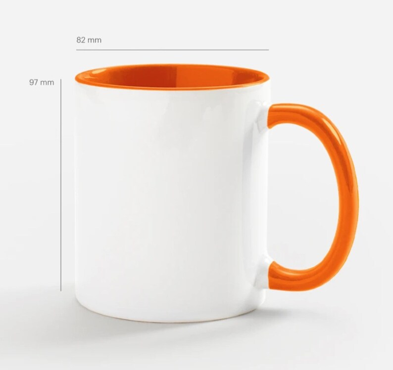 Pode incluir: Uma caneca de cer&acirc;mica branca com uma borda e uma al&ccedil;a laranja. A caneca tem 9,7 cm de altura e 9,1 cm de largura.