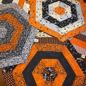 May include: Set of four orange and black Halloween themed hexagon-shaped placemats with a variety of patterns including skeletons, bats, and pumpkins.