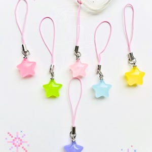 May include: Six pink phone charms with star-shaped charms in various pastel colors, including pink, yellow, green, blue, and purple.
