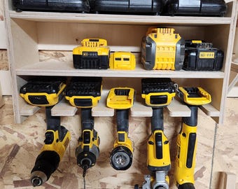 May include: A wooden wall-mounted storage rack with multiple shelves for organizing power tools and batteries. The rack holds six yellow and black cordless drills and several yellow and black batteries.