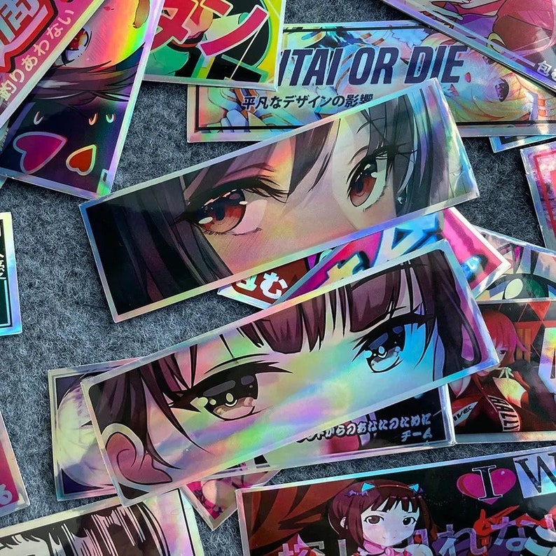 Puede incluir: Una colecci&oacute;n de pegatinas hologr&aacute;ficas con ojos de estilo anime y texto japon&eacute;s. Las pegatinas son coloridas e iridiscentes, con un efecto arco&iacute;ris.