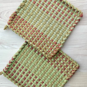 May include: Two woven pot holders in green and red with a braided edge.