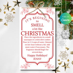 May include: A rectangular sign with red text and a decorative border reads "It's beginning to smell a lot like Christmas." Instructions for a simmer pot are included. The sign is tied with twine and decorated with holiday accents.