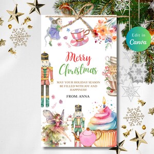 May include: A watercolor Christmas gift tag with a festive design. The tag features a "Merry Christmas" message, illustrations of a fairy, nutcrackers, and a cupcake. The tag is tied with twine and decorated with holiday ornaments.