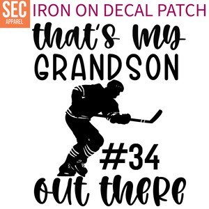 May include: Black and white iron-on decal patch featuring a hockey player with the text "that's my grandson #34 out there".