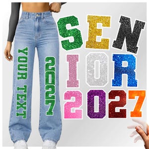 Puede incluir: Vaqueros de mezclilla azul claro con las palabras "YOUR TEXT" y "SENIOR" en letras con purpurina verde. Letras y números de purpurina separados deletrean "SENIOR 2027" en varios colores, incluyendo dorado, negro, rosa, plateado, azul, morado y naranja.