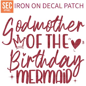 以下が含まれることがあります： 「誕生日人魚のゴッドマザー」というテキストと、王冠とハートが描かれた赤いグリッターアイロン接着パッチです。