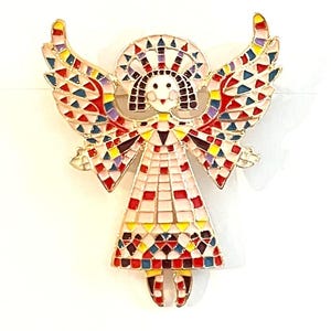 May include: A colorful angel brooch with a gold-tone metal outline. The wings, halo, and dress are decorated with a mosaic pattern of red, yellow, blue, and white. The angel has a smiling face and outstretched arms.