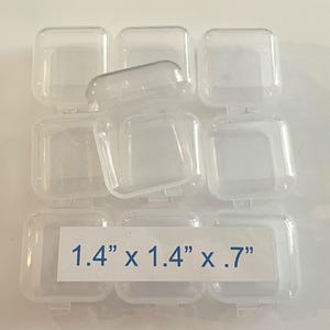 May include: A set of eight clear plastic square containers with hinged lids. The containers are 1.4 inches by 1.4 inches by 0.7 inches.