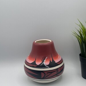 Peut inclure: Un vase en céramique peint à la main avec un motif amérindien. Le vase est rouge, blanc et noir, avec un corps rond en forme de poire et une large ouverture.
