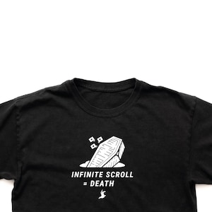 Puede incluir: Camiseta negra con un gráfico blanco de un ataúd y el texto "INFINITE SCROLL = DEATH" debajo. El diseño incluye un pequeño icono de pájaro. La camiseta está hecha de un material suave.