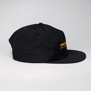May include: A black baseball cap with a yellow embroidered logo that reads "McLaren Formula 1".