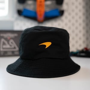 May include: A black bucket hat with a yellow McLaren logo on the front.