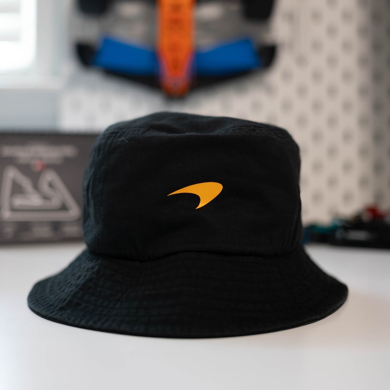 May include: A black bucket hat with a yellow McLaren logo on the front.