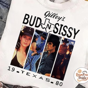 May include: White sweatshirt featuring a graphic from the movie "Urban Cowboy" with the text "Gilley's Bud N Sissy 19-TEXAS-80" and images from the film. The design includes a Texas outline. The sweatshirt is made of a soft material.