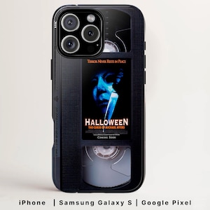 May include: Black phone case featuring a VHS tape design with the movie poster for "Halloween: The Curse of Michael Myers." The case includes the text "Terror Never Rests in Peace" and "Coming Soon."