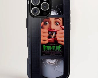 May include: Black phone case featuring a VHS tape design with the movie title "Dead Alive." The case has a glossy finish and a close-up of a person's face with the movie title in green and white.