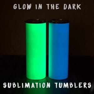 May include: Two glowing tumblers, one green and one blue, are displayed against a dark background. The text "GLOW IN THE DARK" and "SUBLIMATION TUMBLERS" are printed above and below the tumblers. The tumblers have a sleek, cylindrical design.