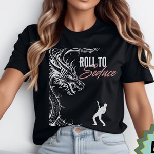 May include: Black t-shirt with a white dragon graphic and the text "Roll to Seduce" in pink lettering. A silhouette of a person playing a guitar is also on the shirt.